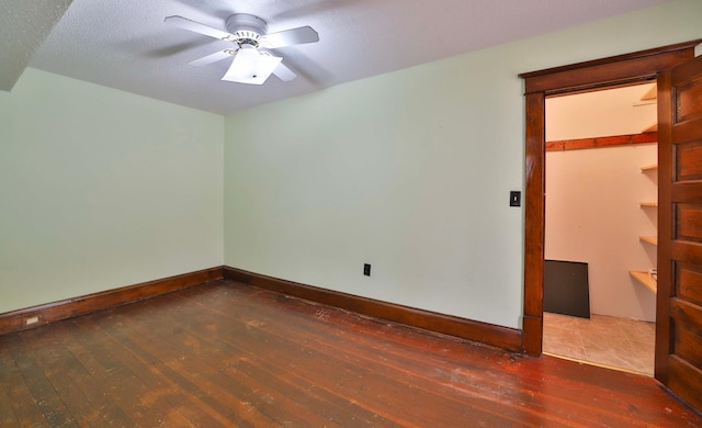 spare room featuring wood-type flooring, a ceiling fan, baseboards, and a textured ceiling
