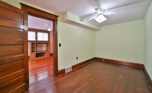 empty room with dark wood-style floors, a textured ceiling, ceiling fan, and visible vents