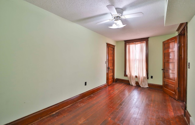 spare room with dark wood-type flooring, a textured ceiling, ceiling fan, and baseboards