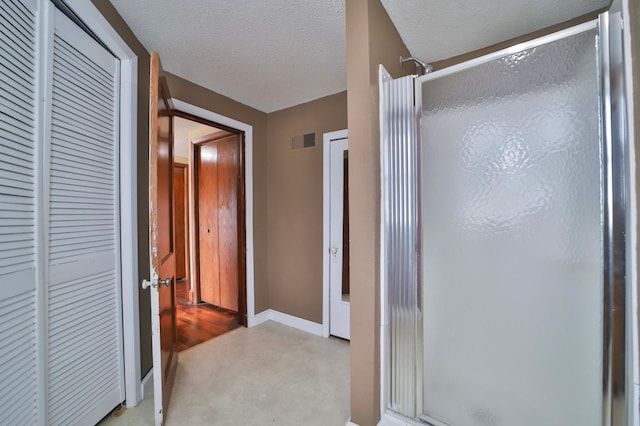 full bath with baseboards, a textured ceiling, visible vents, and a shower stall