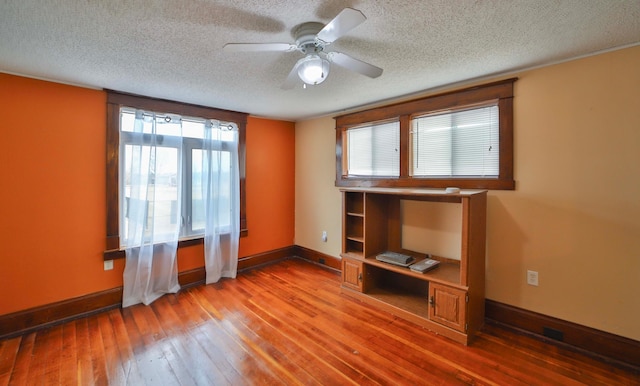 unfurnished bedroom featuring baseboards, a ceiling fan, hardwood / wood-style flooring, and a textured ceiling