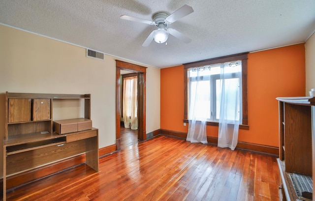 interior space with a ceiling fan, hardwood / wood-style flooring, a textured ceiling, and visible vents