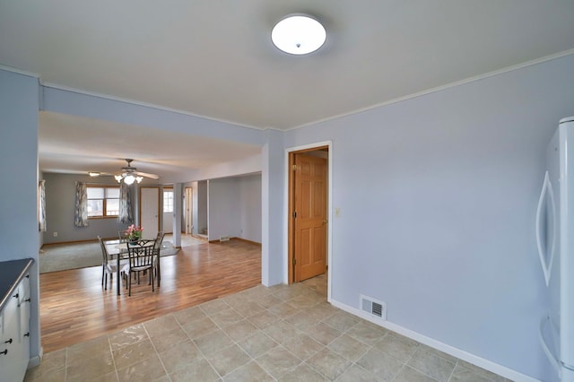 unfurnished dining area with a ceiling fan, ornamental molding, light wood-style floors, and visible vents