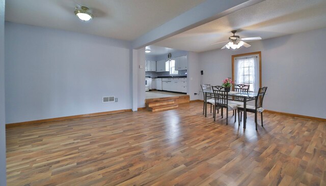 dining space featuring baseboards, visible vents, a ceiling fan, and wood finished floors