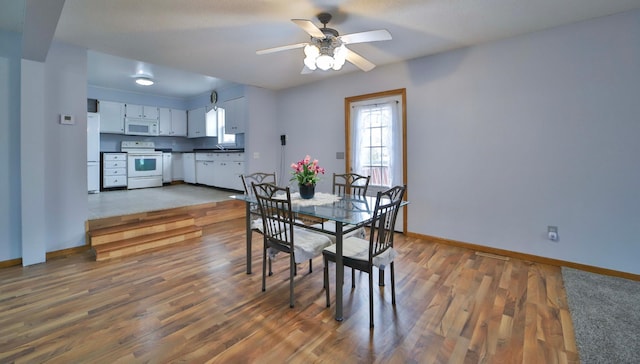 dining space featuring baseboards, wood finished floors, and a ceiling fan