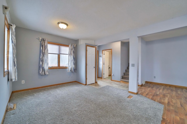 unfurnished room featuring baseboards, carpet floors, and stairway