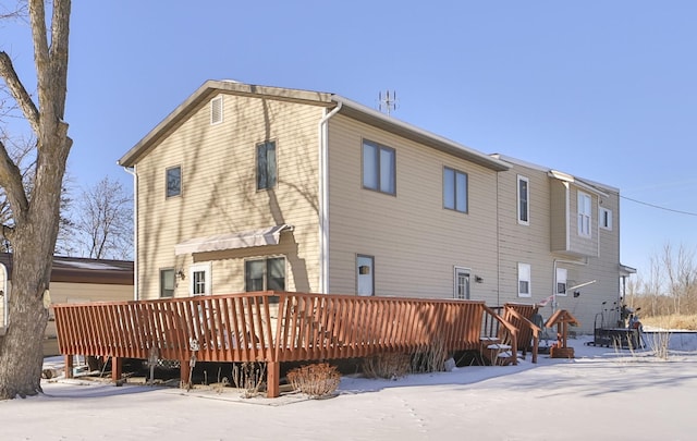 snow covered rear of property with a wooden deck
