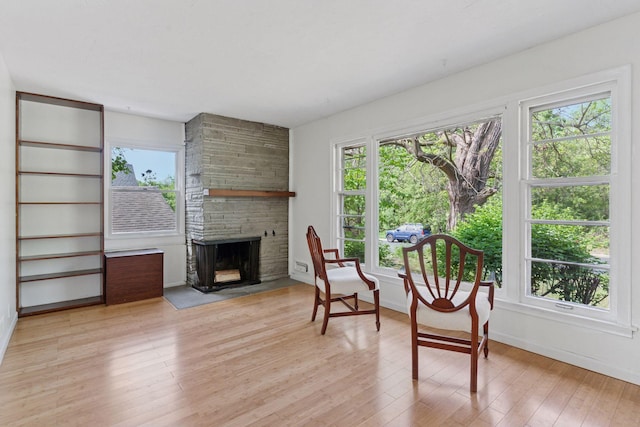 living area with a fireplace, light wood-style floors, and baseboards