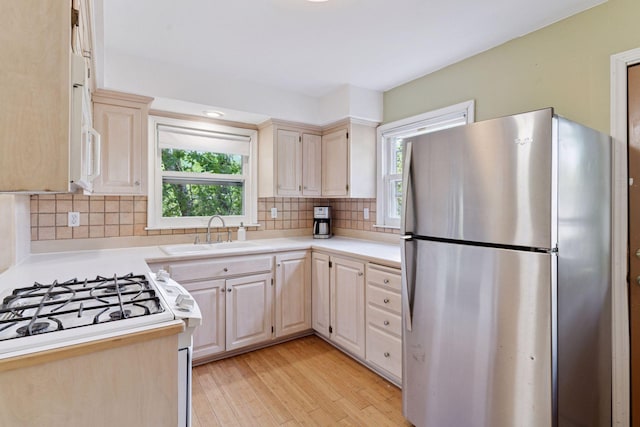 kitchen featuring freestanding refrigerator, a sink, healthy amount of natural light, and light countertops