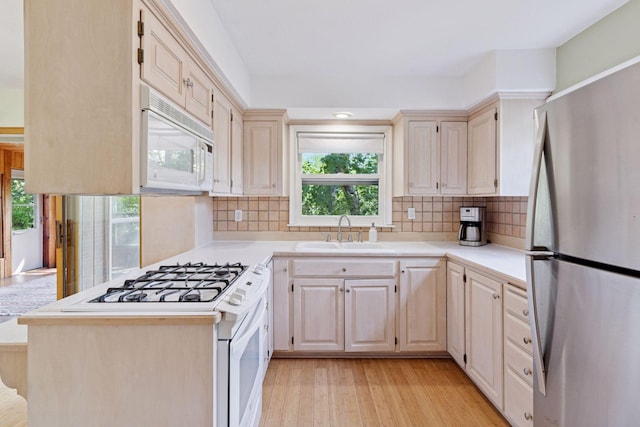 kitchen featuring white appliances, a sink, plenty of natural light, and light countertops