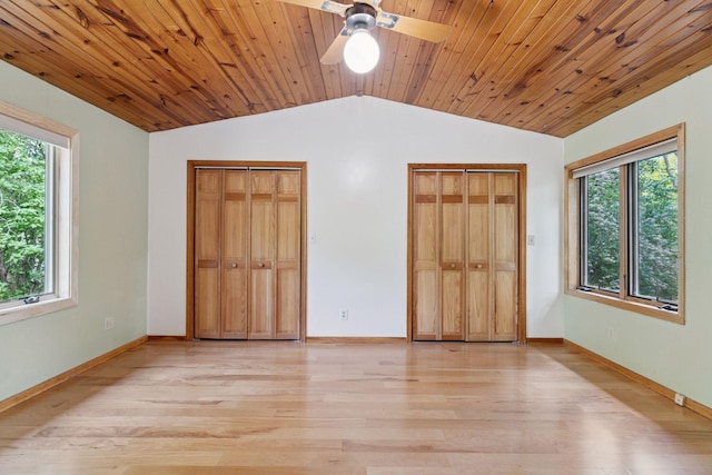 unfurnished bedroom featuring vaulted ceiling, multiple windows, two closets, light wood-style flooring, and baseboards