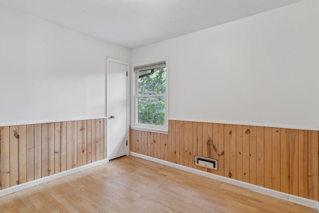 spare room featuring wood finished floors, wainscoting, wood walls, and baseboards