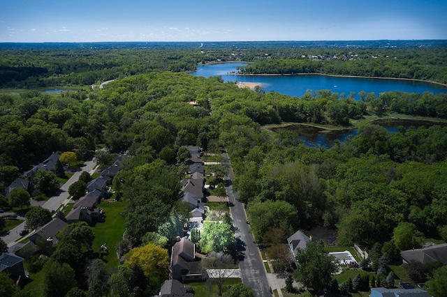 aerial view of property's location featuring a heavily wooded area, a nearby body of water, and nearby suburban area