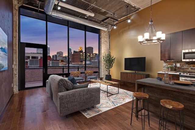 living room with a chandelier, track lighting, expansive windows, a high ceiling, and dark hardwood / wood-style flooring