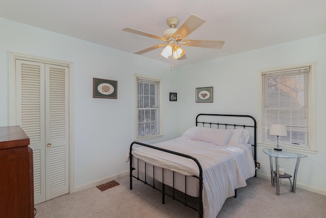 bedroom featuring ceiling fan, a textured ceiling, and light carpet