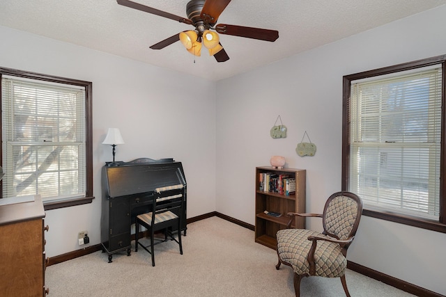 living area with ceiling fan, a textured ceiling, and light carpet