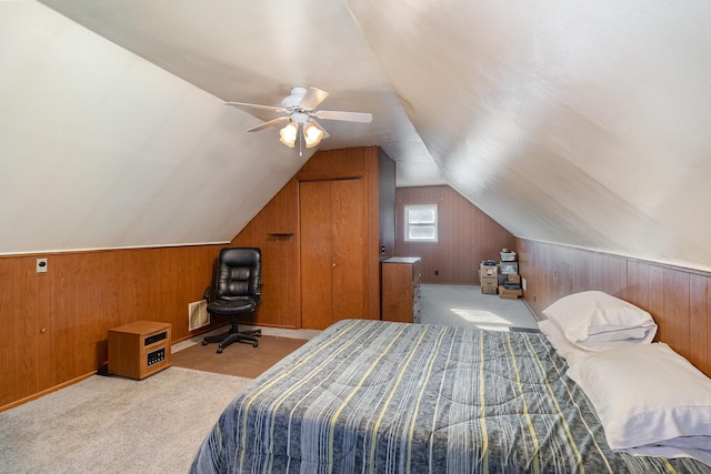 carpeted bedroom with lofted ceiling, wood walls, and ceiling fan