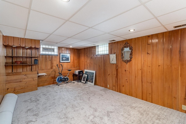 interior space with wooden walls, a drop ceiling, and carpet floors