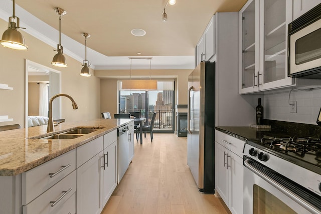 kitchen with sink, white cabinetry, hanging light fixtures, appliances with stainless steel finishes, and light stone countertops