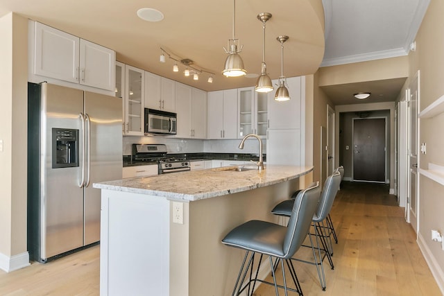 kitchen featuring decorative light fixtures, sink, white cabinets, a kitchen island with sink, and stainless steel appliances