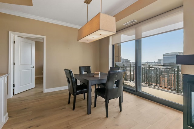 dining space featuring crown molding, plenty of natural light, and light hardwood / wood-style flooring