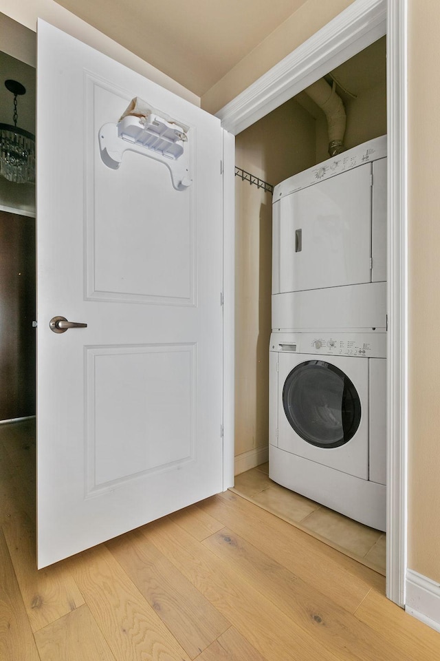 laundry room featuring hardwood / wood-style flooring and stacked washer and clothes dryer