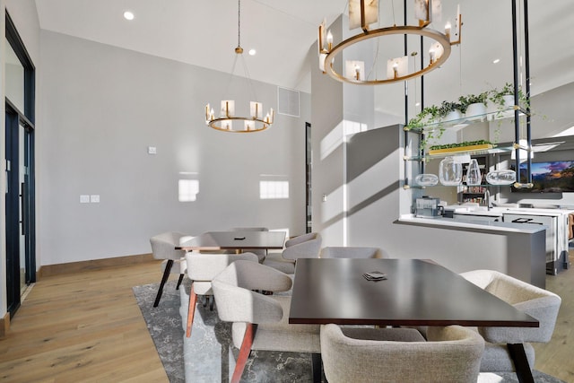 dining area featuring a chandelier, light hardwood / wood-style floors, and a high ceiling