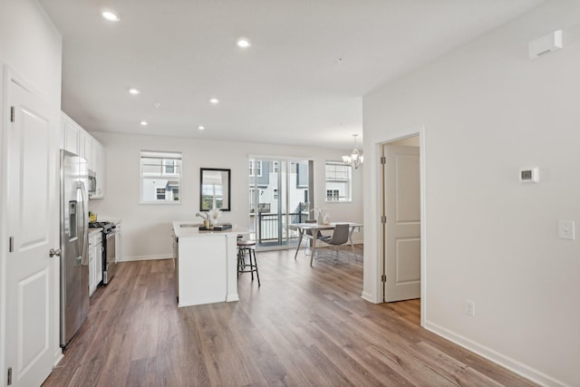 kitchen with white cabinets, a center island, stainless steel appliances, a kitchen breakfast bar, and hanging light fixtures