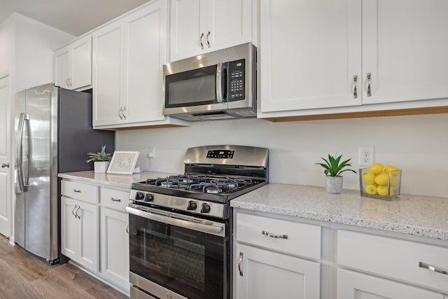 kitchen with white cabinetry, light hardwood / wood-style flooring, light stone countertops, and stainless steel appliances