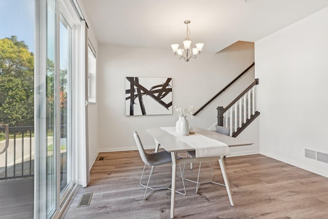 dining space with hardwood / wood-style floors and a chandelier