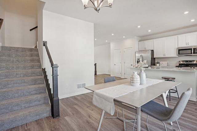 dining space featuring sink, light wood-type flooring, and a notable chandelier