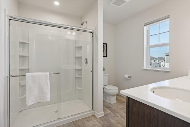 bathroom with vanity, a shower with shower door, and toilet