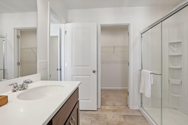 bathroom with hardwood / wood-style floors, a shower with shower door, and vanity