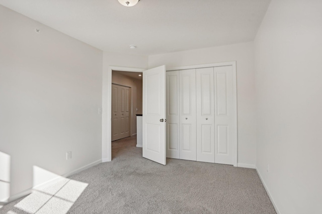 unfurnished bedroom with a closet and light colored carpet