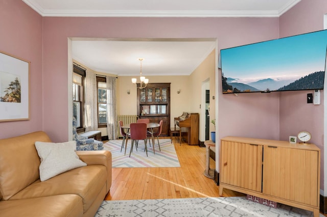 living room featuring a notable chandelier, ornamental molding, and light wood-type flooring