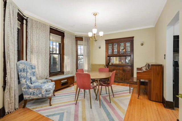 dining area with crown molding, radiator, light hardwood / wood-style flooring, and a notable chandelier