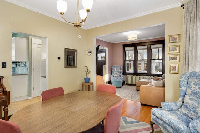 dining area featuring ornamental molding, radiator heating unit, a notable chandelier, and light hardwood / wood-style floors