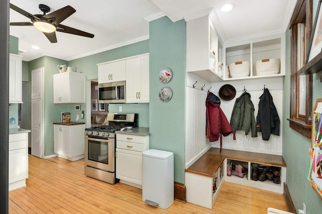 kitchen featuring white cabinets, ornamental molding, ceiling fan, light hardwood / wood-style floors, and stainless steel appliances