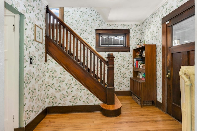 stairs with crown molding, radiator heating unit, and hardwood / wood-style floors