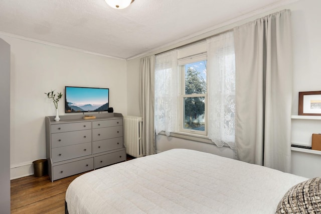 bedroom with wood-type flooring, radiator heating unit, a textured ceiling, and crown molding