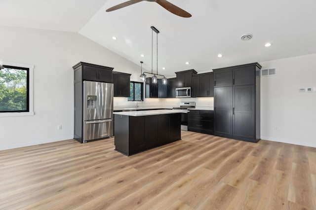 kitchen with light hardwood / wood-style floors, hanging light fixtures, appliances with stainless steel finishes, and a center island