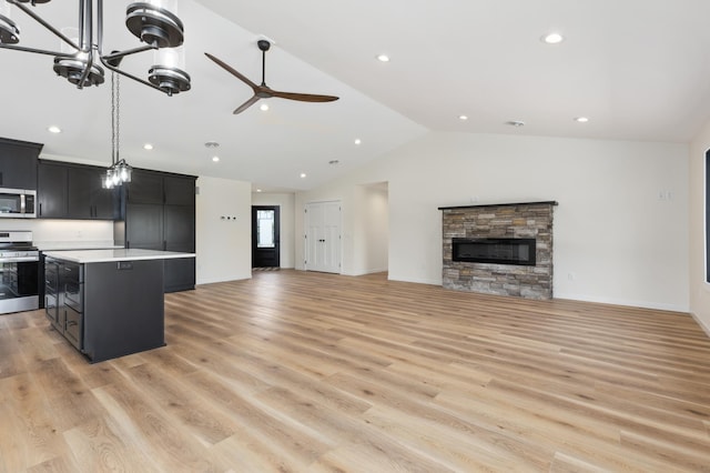 kitchen with a kitchen island, light hardwood / wood-style floors, a stone fireplace, and appliances with stainless steel finishes