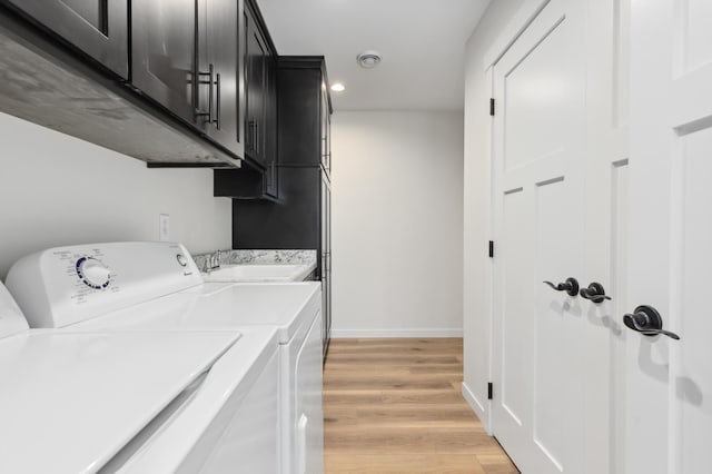 laundry area featuring cabinets, sink, separate washer and dryer, and light hardwood / wood-style floors