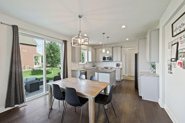 dining room featuring sink, a notable chandelier, and dark wood-type flooring