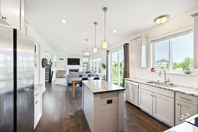 kitchen featuring light stone countertops, tasteful backsplash, sink, a kitchen island, and stainless steel appliances