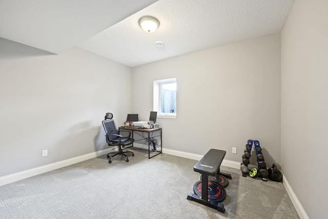 carpeted home office featuring a textured ceiling