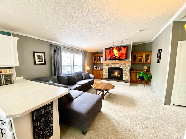 living room with a fireplace, track lighting, ornamental molding, a textured ceiling, and light colored carpet