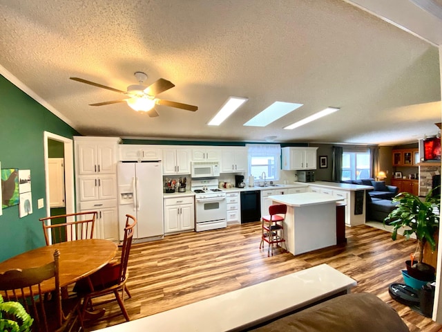 kitchen with white appliances, light hardwood / wood-style floors, a center island, and white cabinets