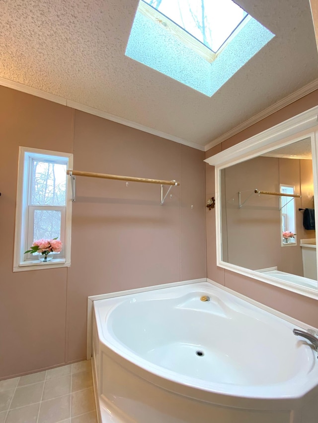 bathroom featuring a bathtub, a skylight, ornamental molding, a textured ceiling, and tile patterned floors