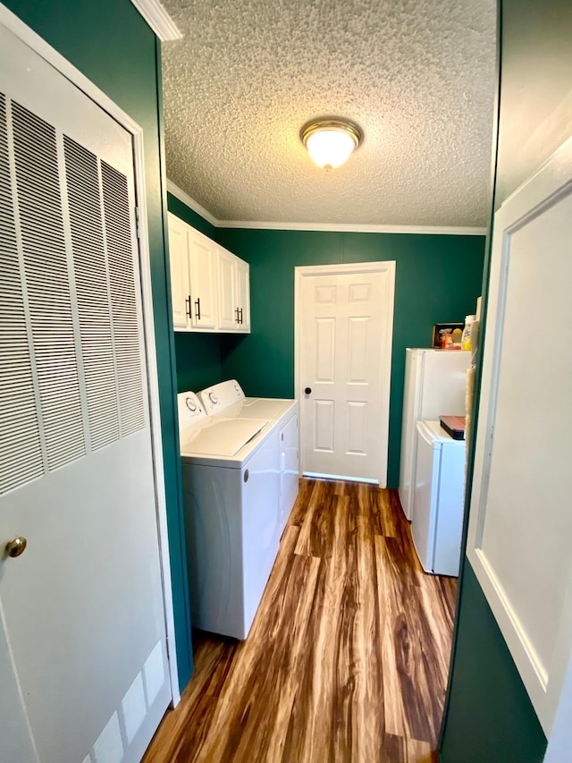 washroom with washer and clothes dryer, cabinets, ornamental molding, a textured ceiling, and dark hardwood / wood-style flooring